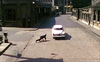 Film: The silver car drives off, pursued by a policeman on foot